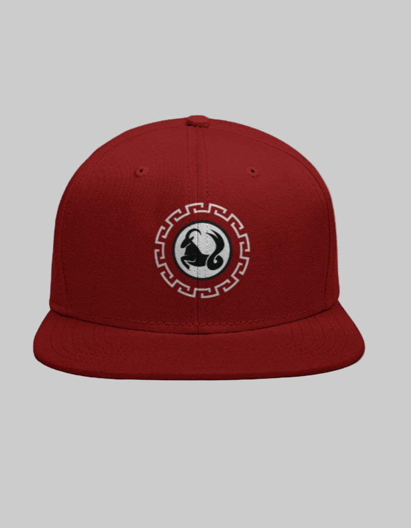 Red snapback cap with black Capricorn mountain goat symbol inside a white geometric circle.
