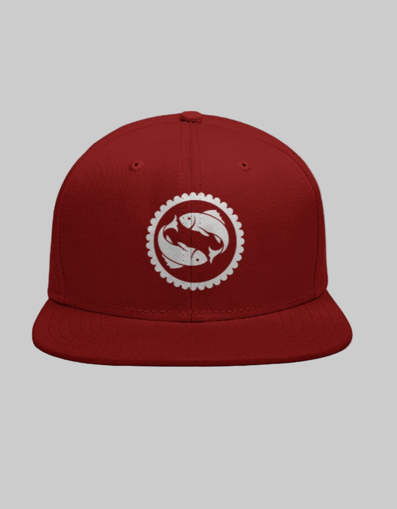 Red snapback cap with twin white fish symbol encased in a mandala-style circular border.