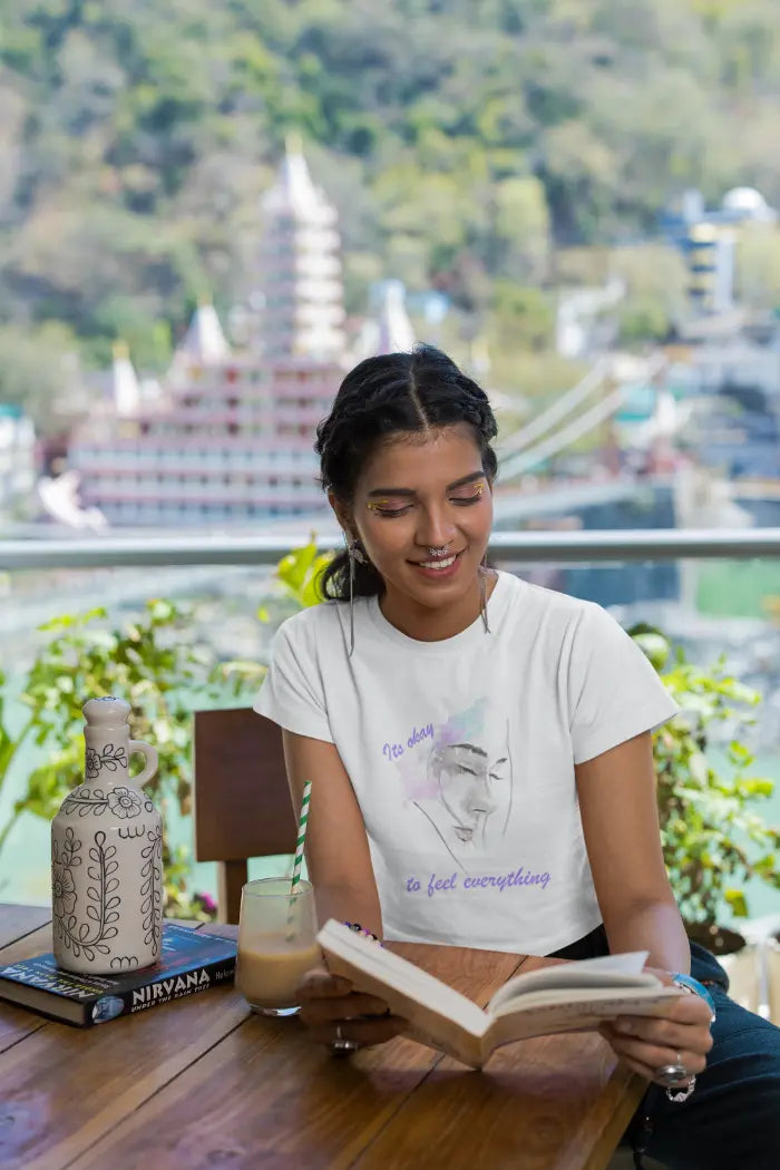 Woman in crop-top reading a book with a scenic background
