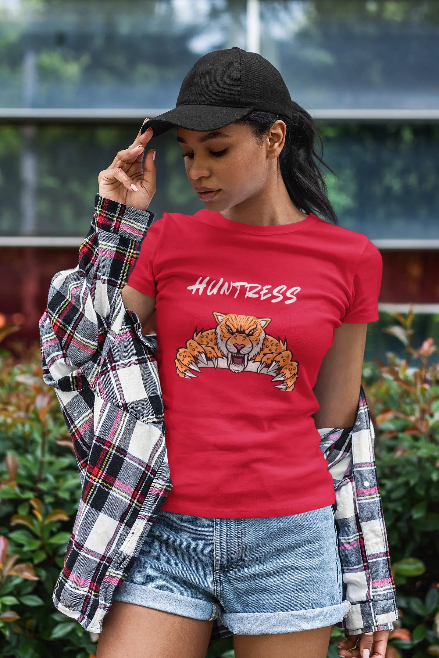 Stylish woman wearing a bold T-shirt with a pouncing tiger graphic and the quote 'Heart of a Huntress' — fierce, empowering streetwear look