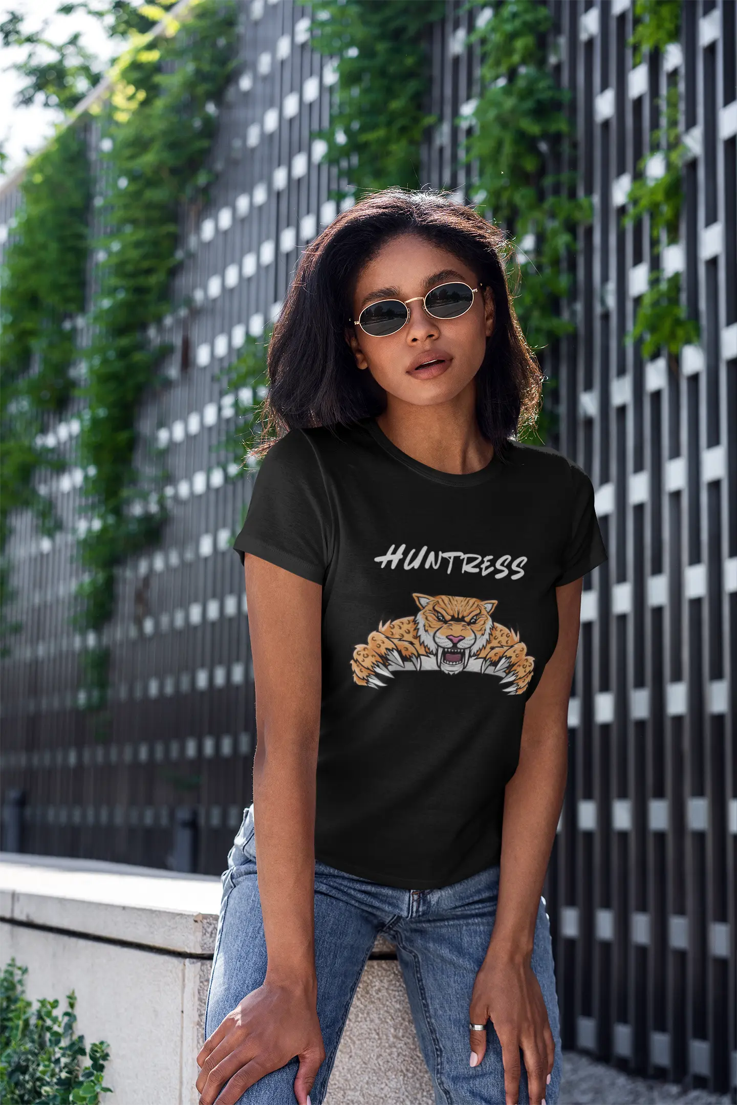 Stylish woman wearing a bold T-shirt with a pouncing tiger graphic and the quote 'Heart of a Huntress' — fierce, empowering streetwear look