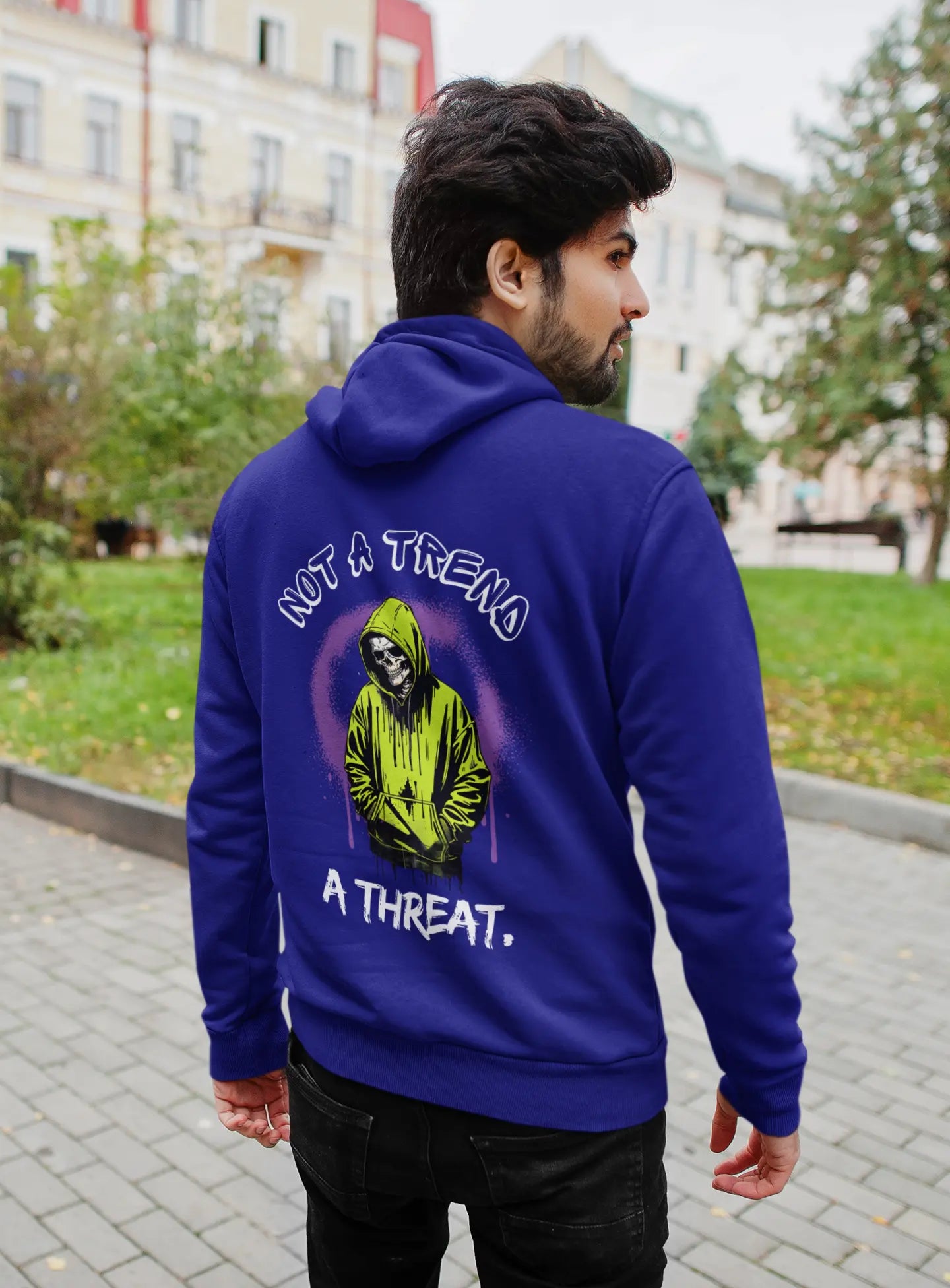Person wearing a blue hoodie with a graphic and text on the back, standing outdoors.