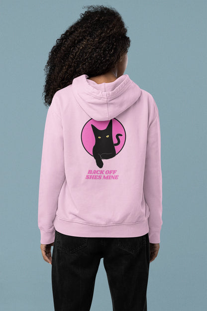 Person wearing a pink hoodie with a black cat graphic and text on the back against a gray background