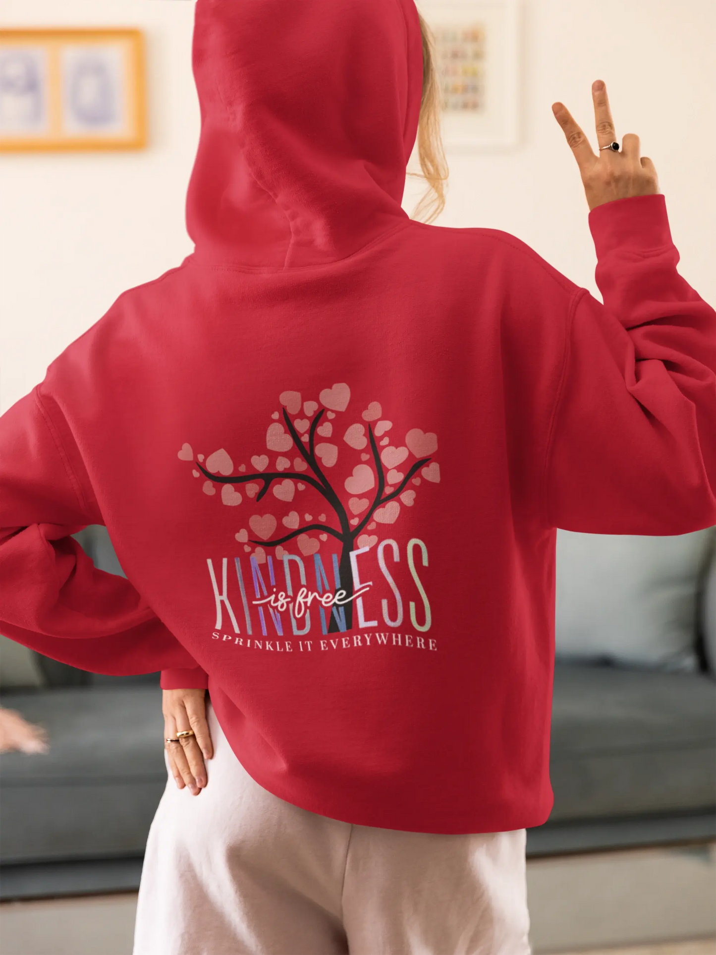 Chill streetwear vibes — woman in oversized hoodie flashing a peace sign, captured in comfy home mood