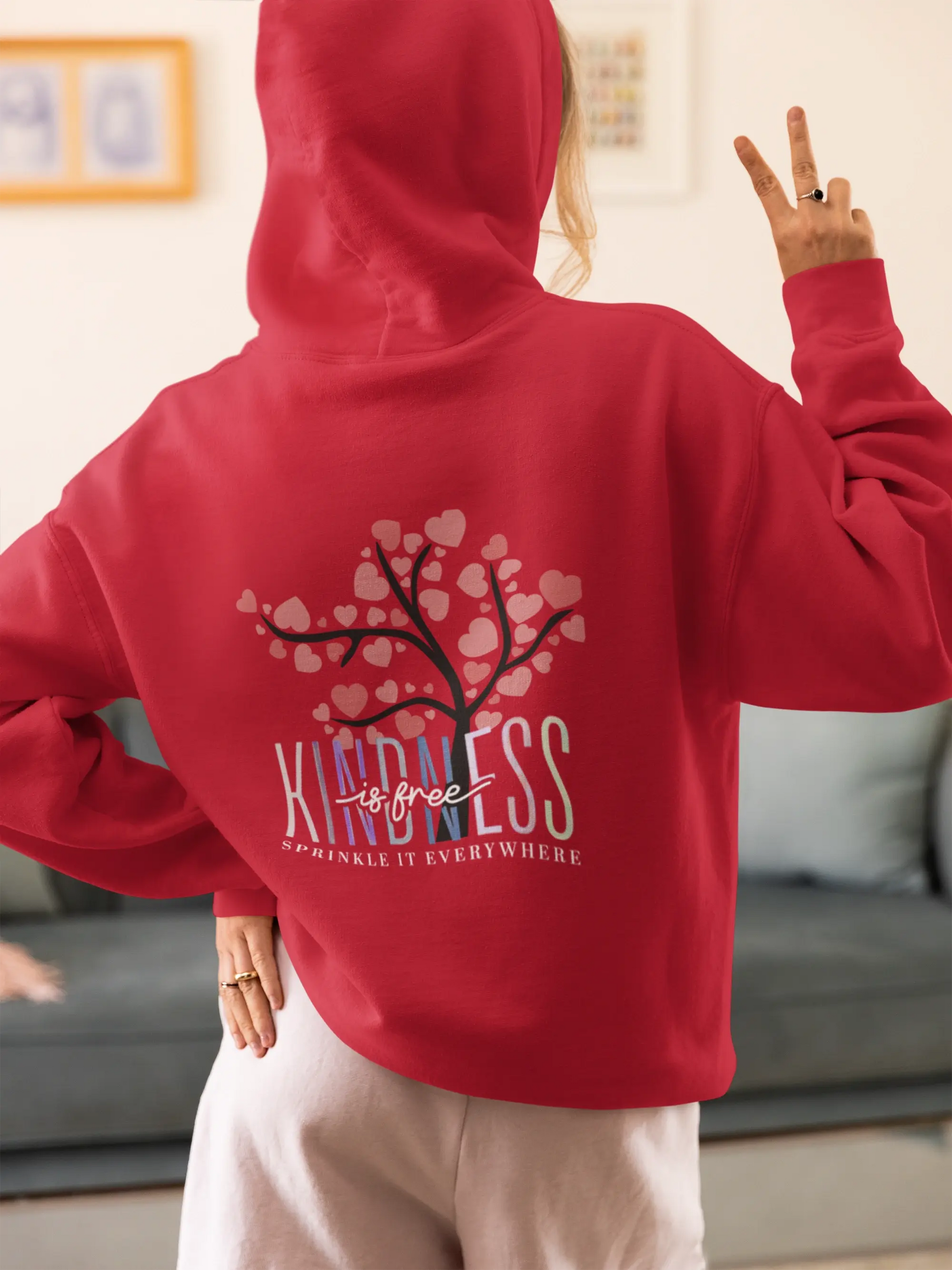 Chill streetwear vibes — woman in oversized hoodie flashing a peace sign, captured in comfy home mood