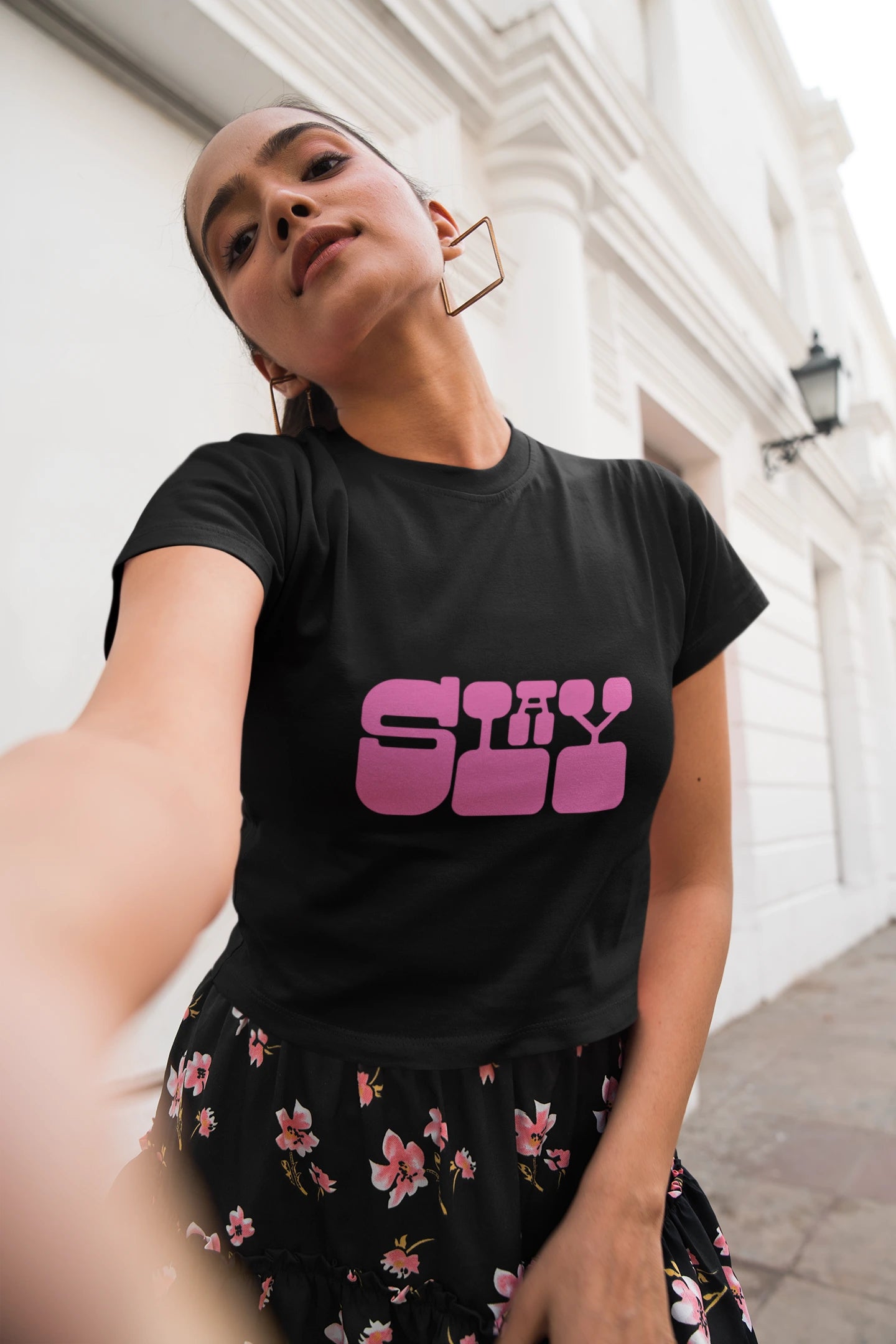 Person wearing a black t-shirt with pink text, standing outdoors.